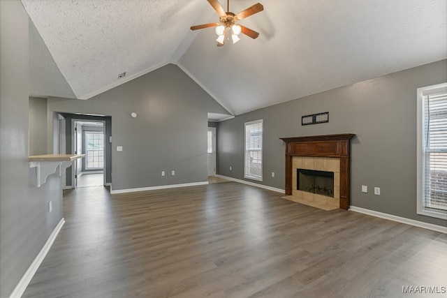 unfurnished living room with lofted ceiling, hardwood / wood-style floors, ceiling fan, a textured ceiling, and a fireplace