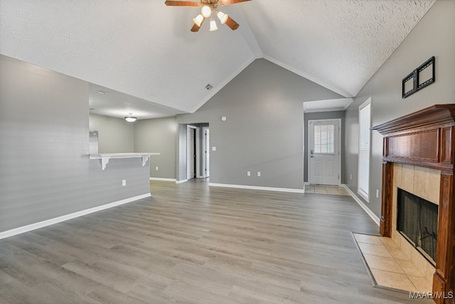 unfurnished living room with light hardwood / wood-style floors, a textured ceiling, a fireplace, and ceiling fan