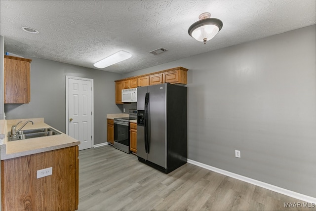 kitchen featuring sink, a textured ceiling, stainless steel appliances, and light hardwood / wood-style floors