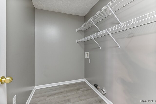 washroom featuring hookup for a gas dryer, a textured ceiling, washer hookup, and light wood-type flooring