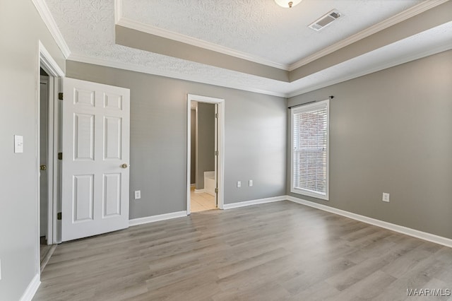 unfurnished bedroom featuring ensuite bathroom, crown molding, a textured ceiling, and light hardwood / wood-style floors