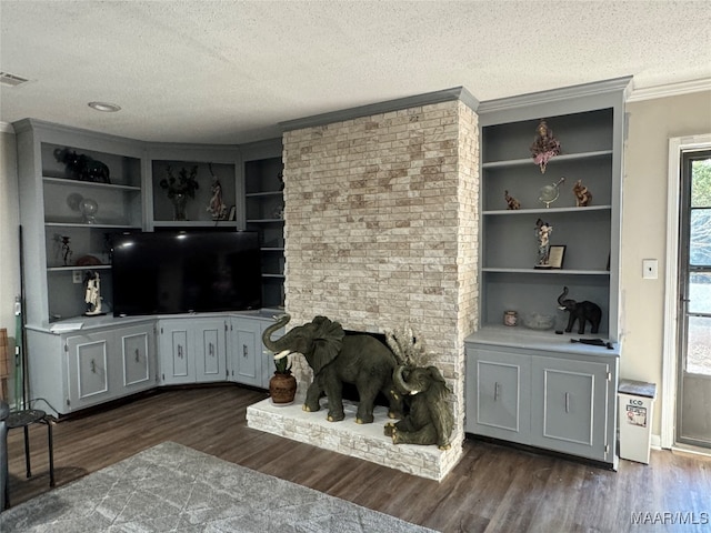 living room featuring ornamental molding, dark hardwood / wood-style floors, a textured ceiling, and built in shelves