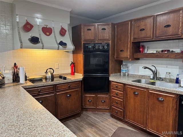 kitchen with black appliances, sink, light hardwood / wood-style floors, crown molding, and decorative backsplash