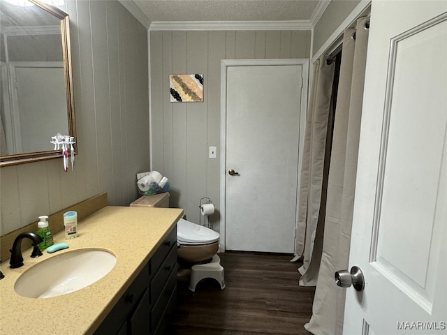 bathroom with hardwood / wood-style floors, a textured ceiling, toilet, ornamental molding, and vanity