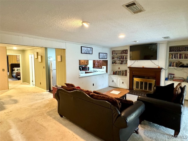 living room featuring a textured ceiling, built in features, and carpet floors