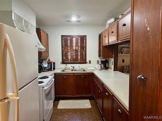 kitchen featuring white appliances, a textured ceiling, and sink