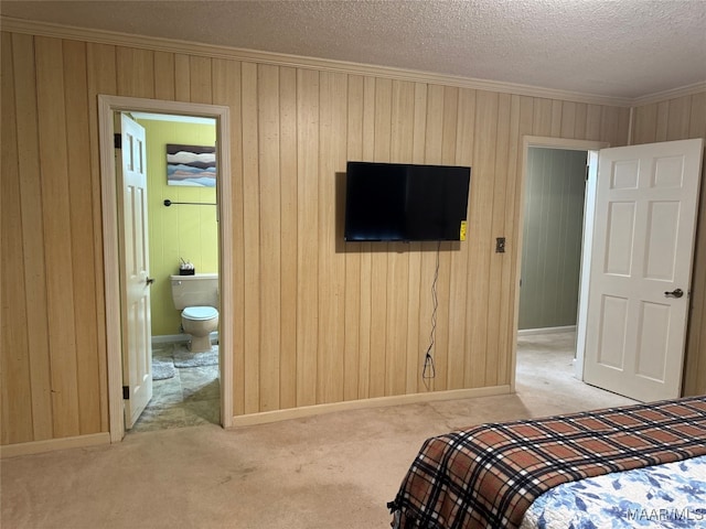 unfurnished bedroom with ensuite bath, light carpet, and a textured ceiling