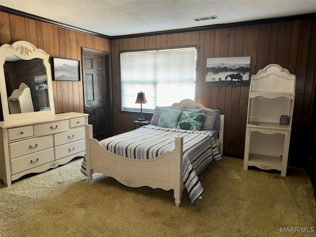 carpeted bedroom featuring ornamental molding, a textured ceiling, and wood walls