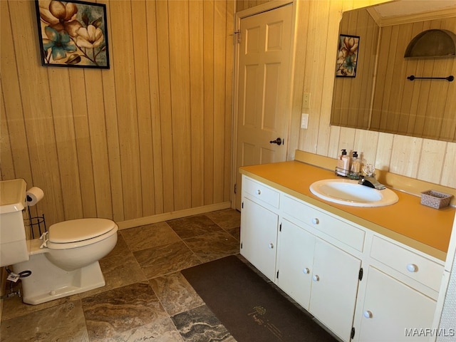 bathroom featuring vanity, toilet, and wood walls