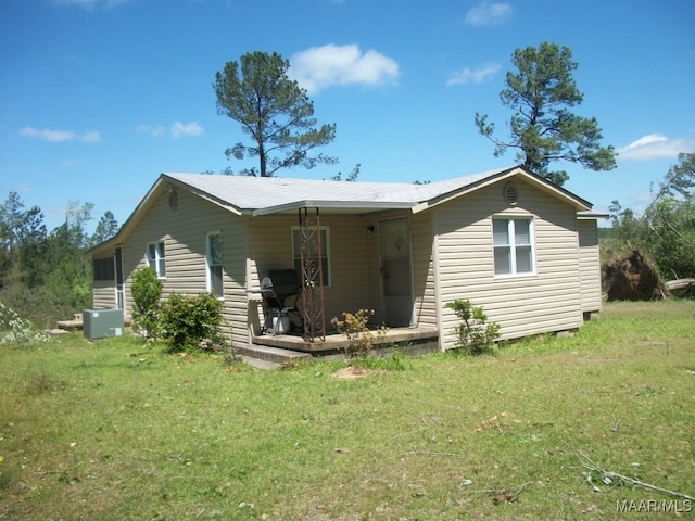 back of property featuring a lawn, central air condition unit, and covered porch