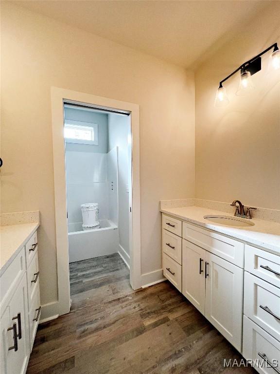 bathroom featuring vanity, hardwood / wood-style flooring, and washtub / shower combination