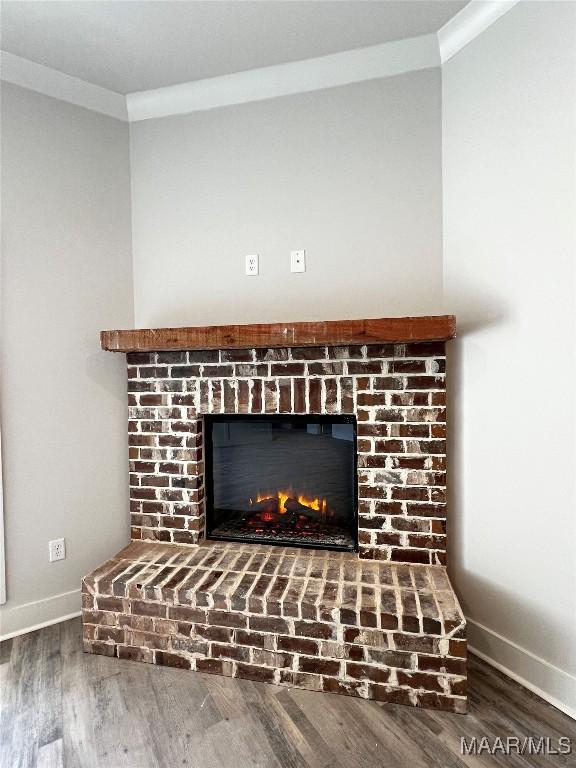 interior details with wood-type flooring, a brick fireplace, and ornamental molding