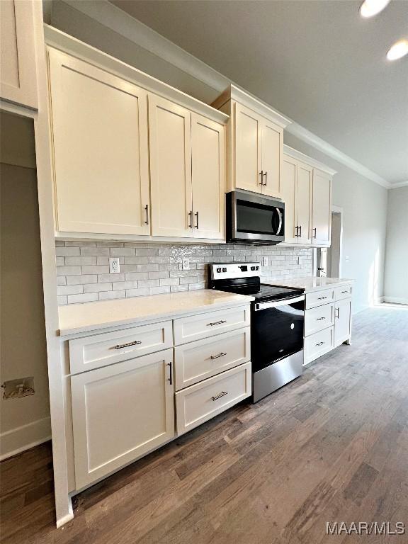 kitchen featuring dark hardwood / wood-style floors, stainless steel appliances, decorative backsplash, white cabinetry, and ornamental molding