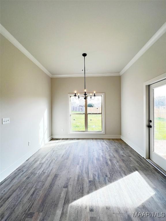 unfurnished dining area featuring a wealth of natural light, dark wood-type flooring, crown molding, and a chandelier