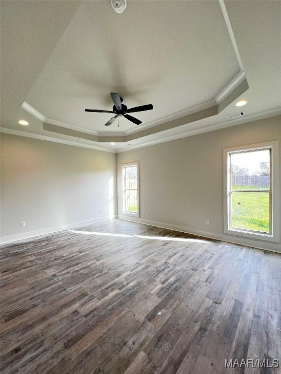 unfurnished room with ornamental molding, ceiling fan, a tray ceiling, and dark hardwood / wood-style flooring