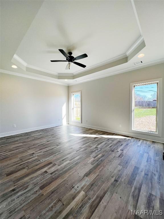 unfurnished room with ceiling fan, dark wood-style flooring, baseboards, ornamental molding, and a raised ceiling