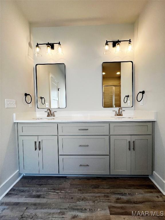 full bathroom with double vanity, a sink, and wood finished floors