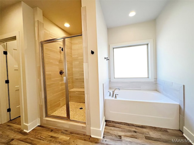 bathroom featuring recessed lighting, a shower stall, wood finished floors, baseboards, and a bath