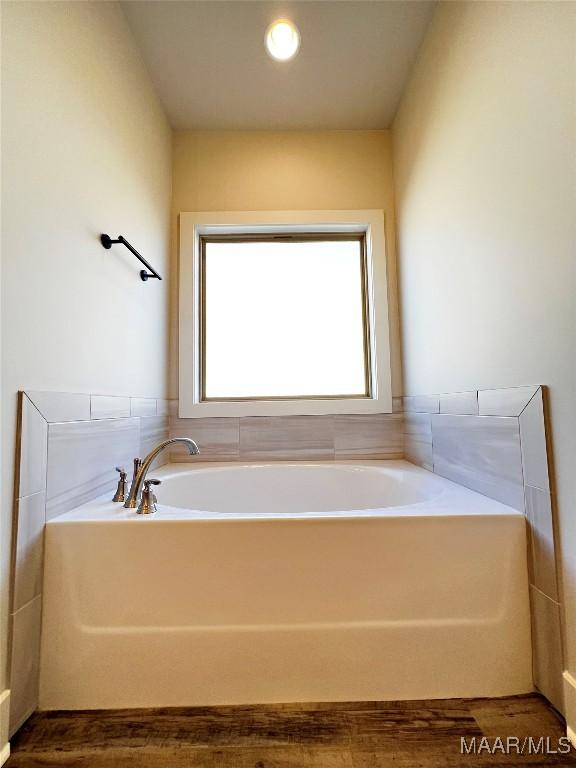 bathroom with wood finished floors and a bath