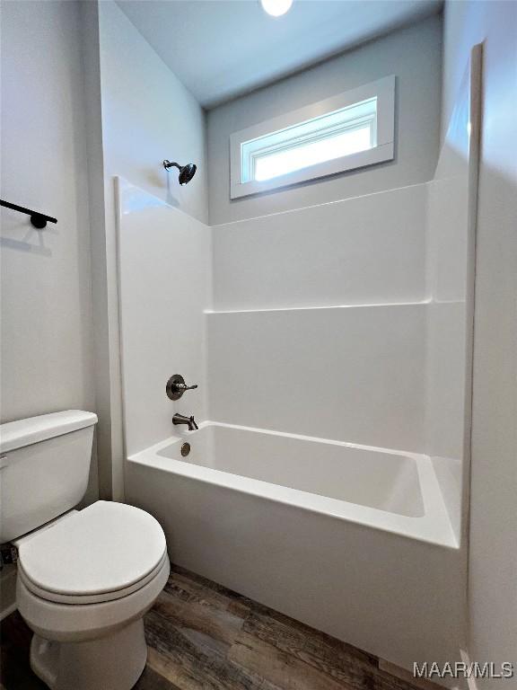 full bath with  shower combination, wood finished floors, and toilet