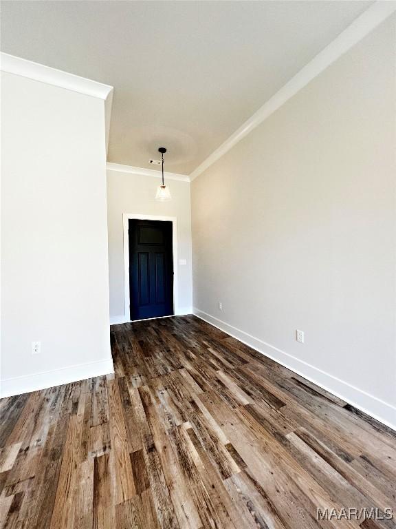 unfurnished room featuring baseboards, wood finished floors, and crown molding