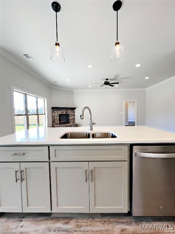 kitchen featuring open floor plan, light countertops, stainless steel dishwasher, and a sink