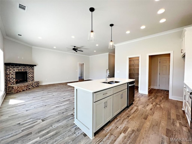 kitchen with a sink, white cabinets, open floor plan, light countertops, and a center island with sink