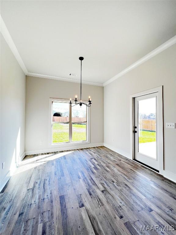 unfurnished dining area featuring a chandelier, crown molding, and wood finished floors