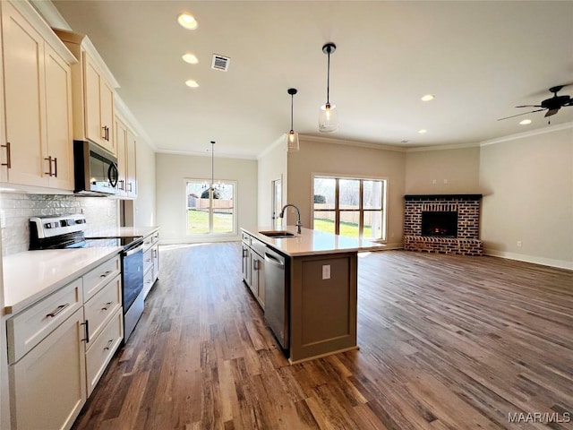 kitchen with stainless steel appliances, a sink, visible vents, light countertops, and an island with sink