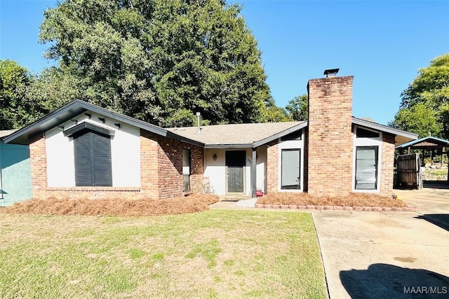 view of front of house featuring a front yard, a chimney, a carport, and brick siding