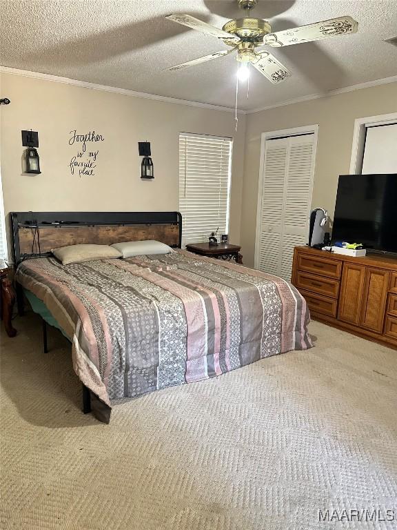 carpeted bedroom with ceiling fan, a closet, ornamental molding, and a textured ceiling