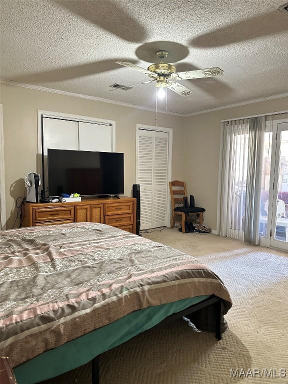 carpeted bedroom featuring access to exterior, crown molding, visible vents, ceiling fan, and a textured ceiling