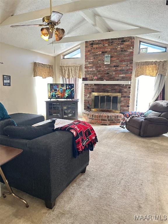 carpeted living room with a textured ceiling, a fireplace, a ceiling fan, and vaulted ceiling with beams