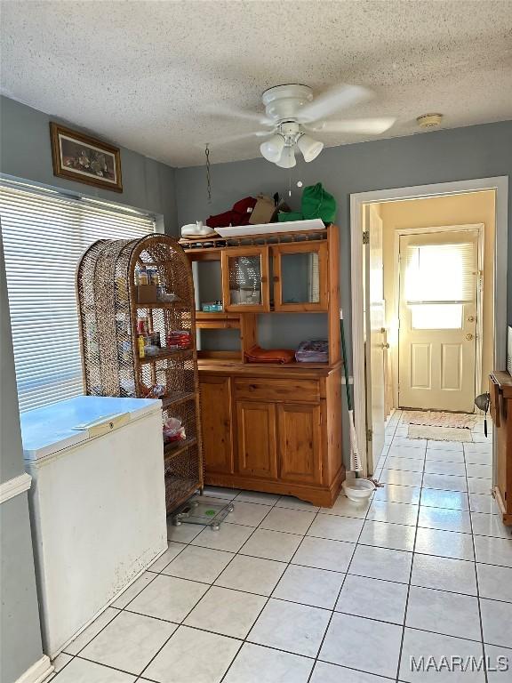 dining space with ceiling fan, a textured ceiling, and light tile patterned floors