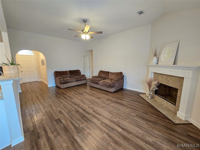 living room with lofted ceiling, ceiling fan, a tile fireplace, and dark hardwood / wood-style flooring