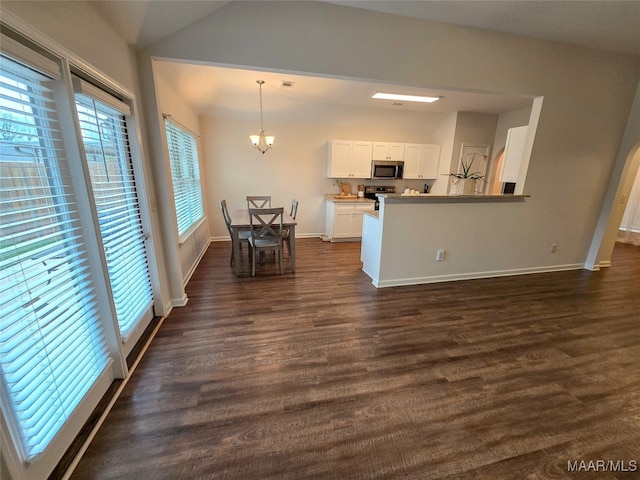 kitchen with appliances with stainless steel finishes, white cabinets, pendant lighting, and dark hardwood / wood-style flooring