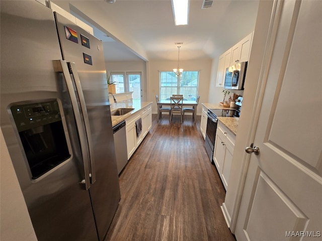 kitchen with hanging light fixtures, stainless steel appliances, sink, white cabinets, and dark hardwood / wood-style flooring