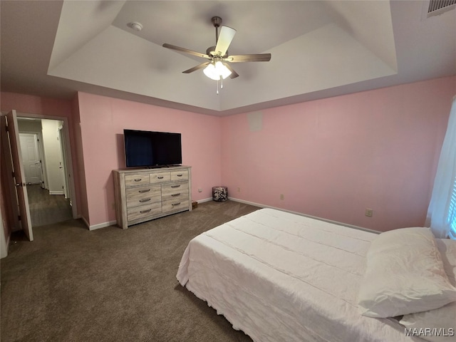 carpeted bedroom featuring a tray ceiling and ceiling fan