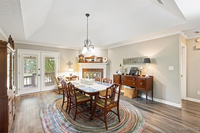 dining space featuring a raised ceiling, french doors, a fireplace, and dark hardwood / wood-style flooring