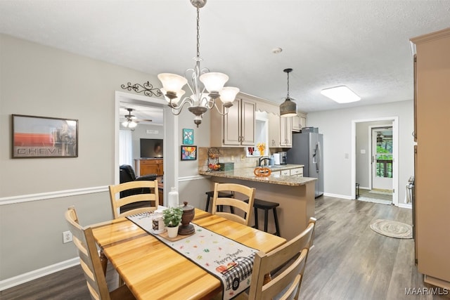 dining space with a textured ceiling, sink, dark wood-type flooring, and ceiling fan with notable chandelier