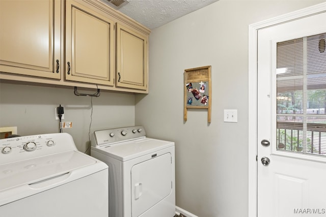 laundry area featuring washer and dryer, a textured ceiling, and cabinets