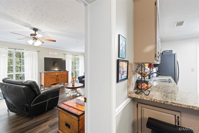 living room featuring ceiling fan, a textured ceiling, sink, and dark hardwood / wood-style floors