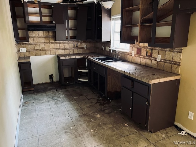 kitchen featuring tasteful backsplash, dark brown cabinets, sink, and tile counters