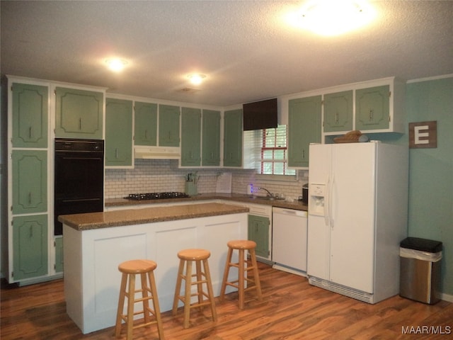 kitchen featuring a center island, black appliances, a breakfast bar area, and green cabinets