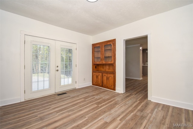 empty room featuring hardwood / wood-style floors, french doors, and a textured ceiling