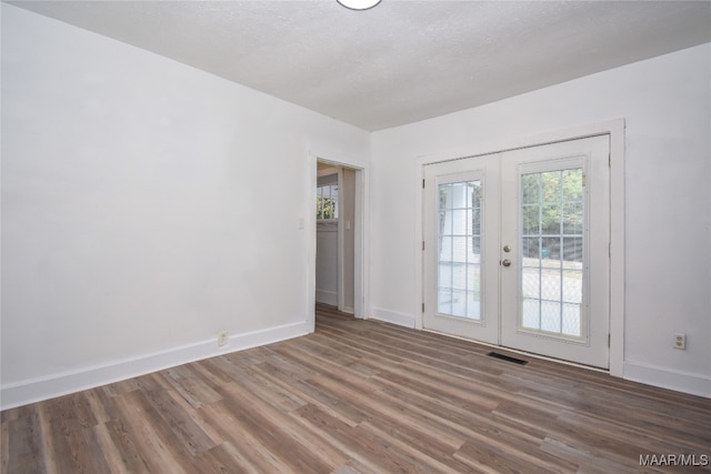 spare room featuring french doors, a textured ceiling, and dark hardwood / wood-style flooring