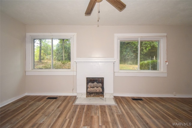 unfurnished living room featuring dark wood-type flooring, ceiling fan, and plenty of natural light