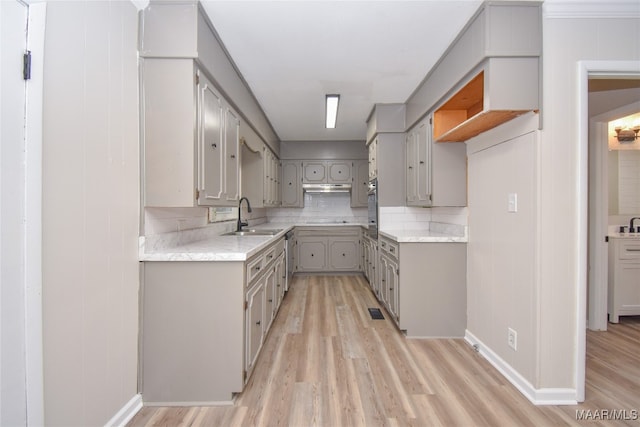 kitchen featuring tasteful backsplash, appliances with stainless steel finishes, sink, light wood-type flooring, and gray cabinets