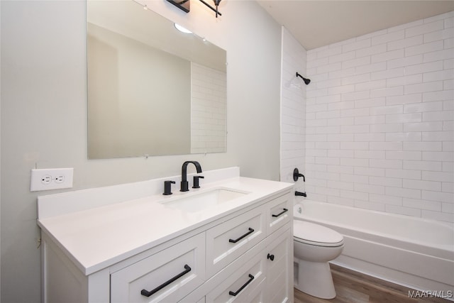 full bathroom featuring toilet, tiled shower / bath, hardwood / wood-style floors, and vanity