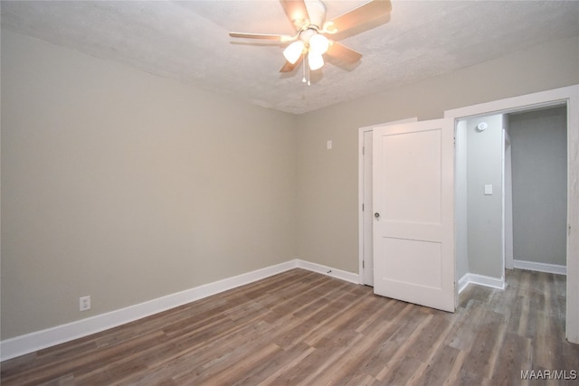 empty room featuring a textured ceiling, dark wood-type flooring, and ceiling fan